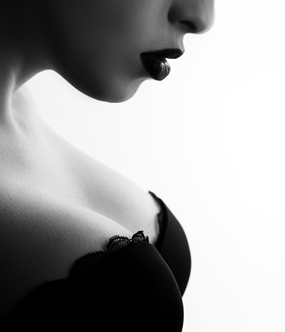 Black and white photo of a woman looking down in a black bra