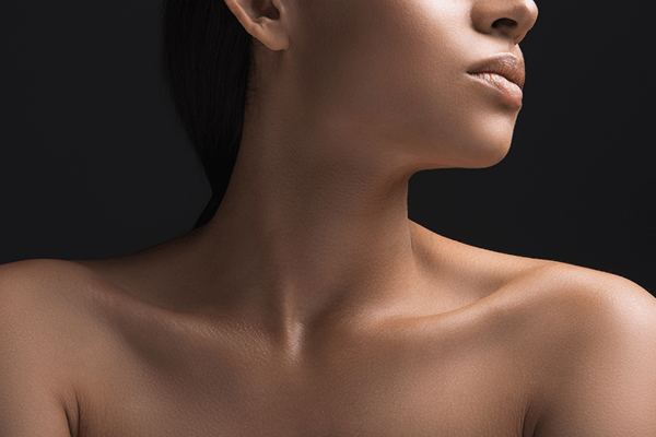 Closeup of a young naked woman with her chin lifted showing the ideal neckline